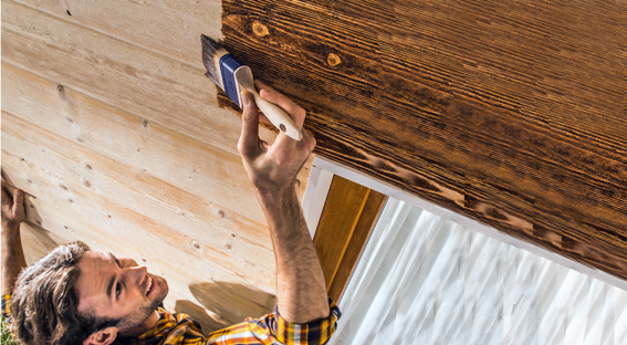 Mann beim Streichen von Holzfassade